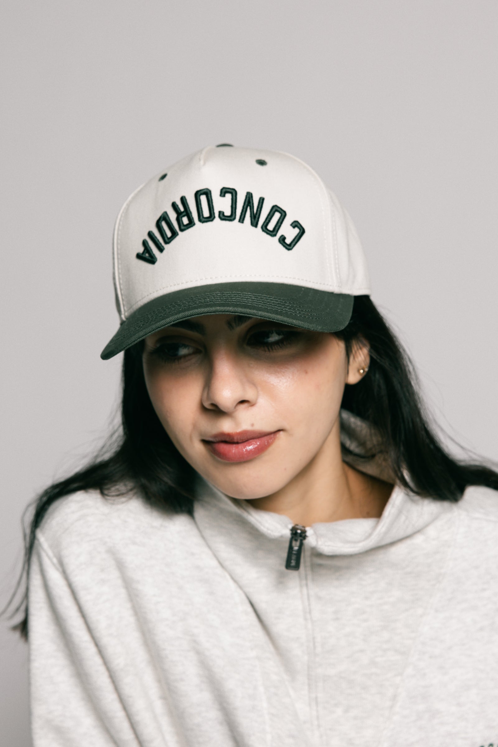 Person wearing a white cap with 'CONCORDIA' text on a gray background